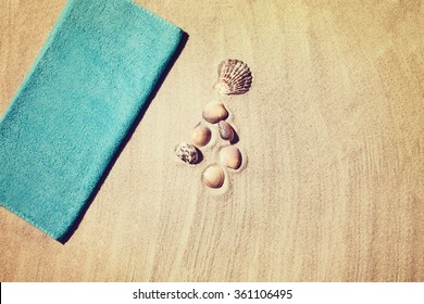 Top view photograph of sandy beach with summer accessories and copy space around objects. Horizontal photo taken from above with visible sand texture. Vintage, retro effect processing.