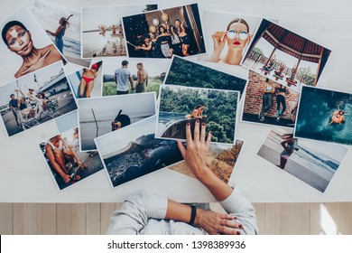 Top view of a photographer selecting best photos from several photo shoot. Female photographer working in studio looking at the prints lying on desk. - Shutterstock ID 1398389936