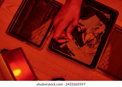 top view of photographer taking freshly developed photo paper in chemical solution with tweezers - Powered by Shutterstock