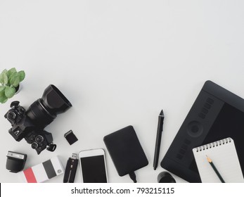 Top View Of Photographer Work Station, Work Space Concept With Digital Camera, Book, Memory Card, Smartphone, Graphic Tablet, External Harddisk On White Background