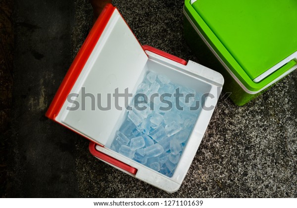 Top view of picnic cooler box with and\
ice cube on the ground for camping during summer vacation time.\
Concept of Holiday, vacations and\
refreshing.