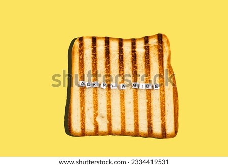 Top view piece of bread toasted in toaster with inscription acrylamide. Concept of  formation of carcinogens when heating bread.