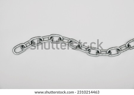 Top view of piece of strong silver metal chain placed on gray background