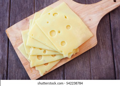 Top View Of Pile Of Swiss Cheese Slices On A Wooden Table.