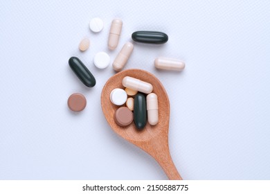 Top view Pills and tablets in wooden spoon on white background.