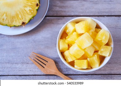 Top View Of Pineapple Chunks In A Bowl On A Wooden Table.