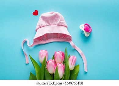 Top View Of Pink Baby Hat And Tulips Near Nipple On Blue Background, Concept Of Mothers Day