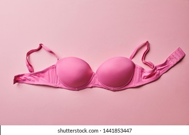 top view of pink brassiere on light pink background, breast cancer concept