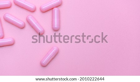 Top view of pink capsule on pink background with copy space. Pharmacy banner. Online pharmacy. Pink background for love addict and women health and insurance topics. Vitamins and supplements concept.