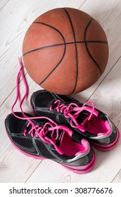 Top View Of Pink Sneakers And Basket Ball On Bright Wooden Floor