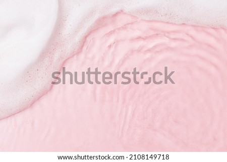 Top view of pink transparent clear calm water surface. Texture with splashes, foam and bubbles. Trendy abstract spring summer nature background for product. Flat lay cosmetic mockup