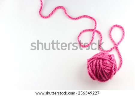 Top view of pink yarn ball with woolen thread on white background 