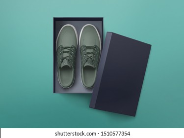 Top view of plain shoe box mockup on green background. Green pair of shoes inside shoe box.