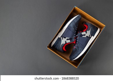 Top View Of Plain Shoe Box Mockup On Grey Background. New Pair Of Insulated Sneakers Inside Shoe Box. Space For Text. Top View.