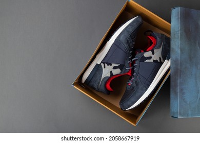 Top View Of Plain Shoe Box Mockup On Grey Background. New Pair Of Insulated Sneakers Inside Shoe Box. Space For Text. Top View.