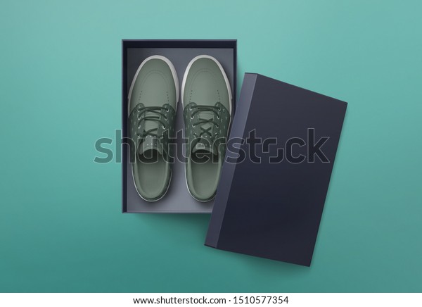 Top view of plain shoe box mockup\
on green background. Green pair of shoes inside shoe\
box.