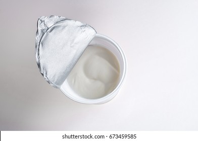 Top view of plastic container with tasty dessert or white sour cream isolated on white background