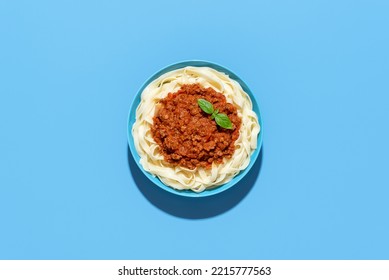 Top view with a plate of bolognese pasta on a blue plate minimalist on a colorful table. Delicious italian dish, tagliatelle with ragu sauce. - Shutterstock ID 2215777563