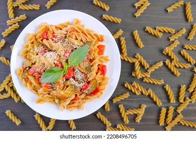 Top View of a Plate of Delectable Fusilli Pasta in Tomato Sauce with Dried Pastas Scattered Around