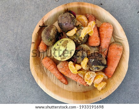 Top view of a plate full of rotten fruits and vegetables like carrots,beetroots,kholrabi,orange isolated on grey background