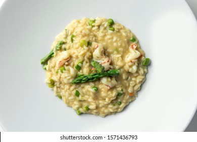 Top View Of Plate Of Risotto With Green Asparagus And Prawns Isolated On White Background