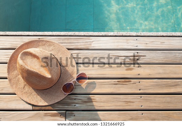 Top view of poolside,\
sun hat and sunglasses on wooden floor with copy space for text or\
word advertising
