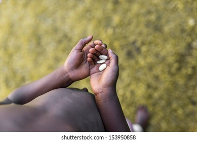 Top View Of Poor African Child Hands Holding Three White Beans. Concept Of Hunger In Africa.