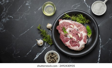 Top view of pork chops with seasonings including garlic, pepper, salt and rosemary on black plate, prepared dinner on black marble background - Powered by Shutterstock