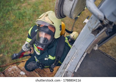 Top View Portrait Of Firefighter In Safe Helmet Going Up On Stairs With Full Equipment