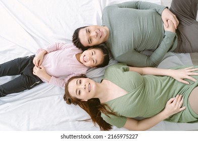 Top View Of Portrait Of Happy Asian Looking At Camera And Smiling While Lying On The Floor At Home. Korean Or Japanese Family Enjoying Free And Relax Time With Happy Moment. Weekend Lifestyle Concept.