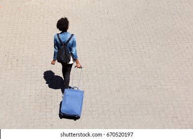 Top view portrait of young afro american woman walking on the street with luggage