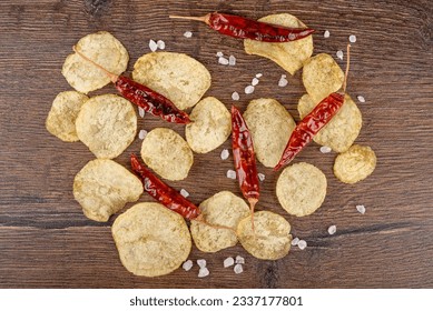 Top view of potato chips, coarse salt and hot pepper pods on a wooden background. - Powered by Shutterstock