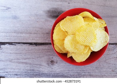 Top View Of Potato Chips In Red Bowl On Wooden Background.