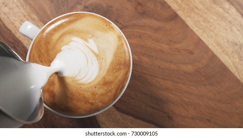 Top View Pour Steamed Milk Into Cappuccino On Wood Table