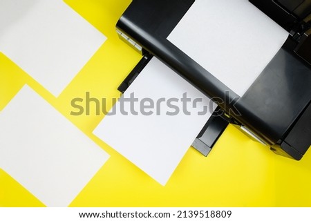 Top view of the printer and blank sheets of paper on a yellow background