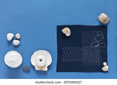 Top View Of The Process Of Hand Sashiko Embroidery In Japanese Style With White Threads On Blue Cotton Fabric On Blue Background. DIY Concept. Flat Lay, Closeup, White Background, Mock Up