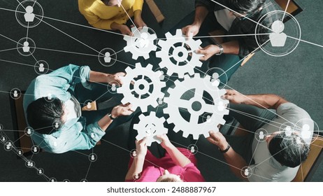 Top view of professional business people joining and gathering wooden gear together. Aerial view of diverse team working together to put or collect cog with network connection holographic. Symposium. - Powered by Shutterstock