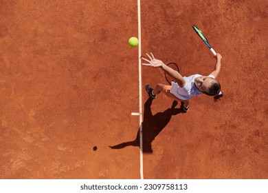 Top view of a professional female tennis player serves the tennis ball on the court with precision and power - Powered by Shutterstock