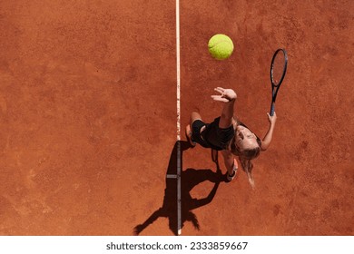 Top view of a professional female tennis player serves the tennis ball on the court with precision and power - Powered by Shutterstock