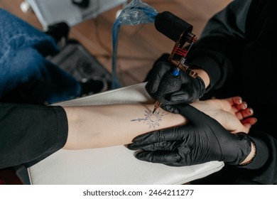 Top view of a professional tattoo artist making a tattoo with a tattoo machine on a woman's forearm. - Powered by Shutterstock