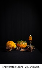 Top View Of Pumpkins With Autumn Leaves And Lit Candle, On Tablecloth And Black Background, Vertical, With Copy Space