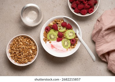 Top View of Raspberry Yogurt in White Bowl with Fresh Kiwi Topping and Ripe Raspberries on Beige Background, Healthy Dessert and Breakfast Concept
