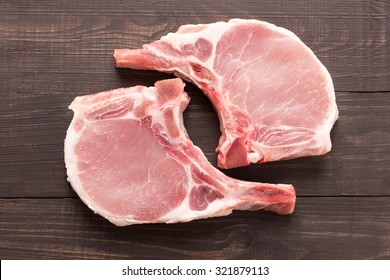 Top View Raw Pork Chop Steak On Wooden Background.