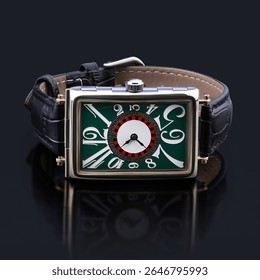 Top view of a rectangular wristwatch with an artistic green dial, expressive typography, and black crocodile-pattern leather strap. An eye-catching piece of luxury fashion design.
