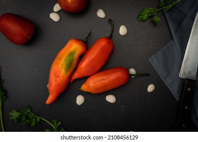 A Top View Of Red Chili Peppers On A Black Messy Kitchen Table