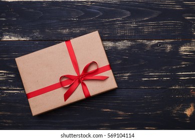 Top view of red classic present box wrapped in a vintage brown paper tied with satin red ribbon isolated over grunge wooden flat layout  - Powered by Shutterstock