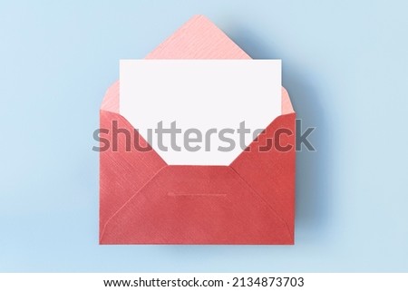 Top view of red envelope with empty blank white card on light blue background, copy space