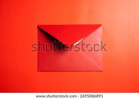Top view of red envelope or postcard on red background. Mockup, blank template, copy space. Greeting or invitation card with flat lay style