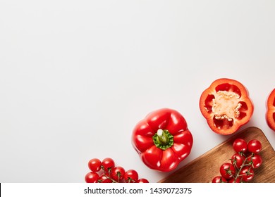 Top View Of Red Organic Vegetables And Wooden Chopping Board On White Background