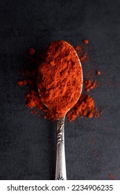 Top view of red paprika powder in spoon on black background with copy space - Shutterstock ID 2234906235